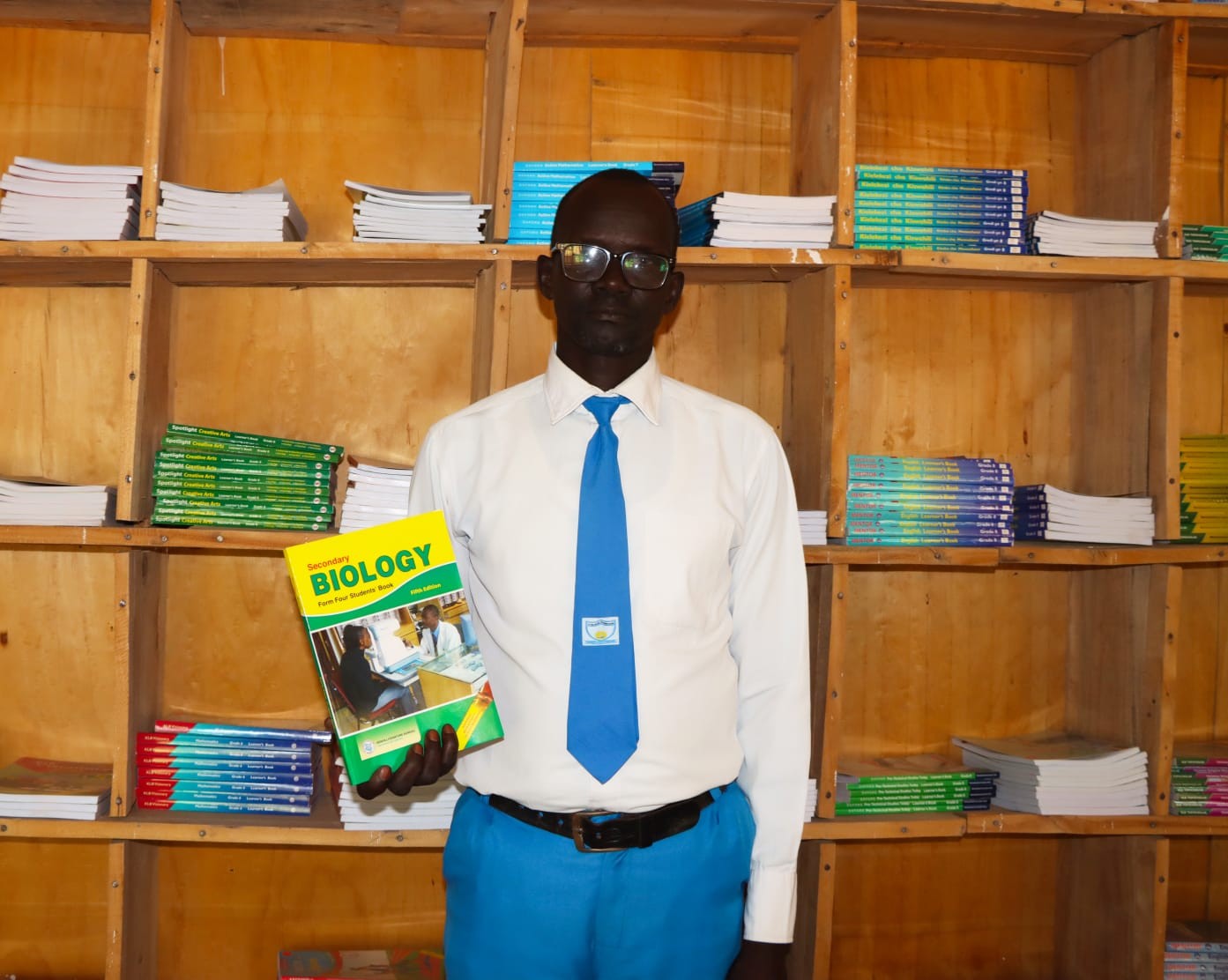 A student holding a Biology textbook in the school learning resource area.